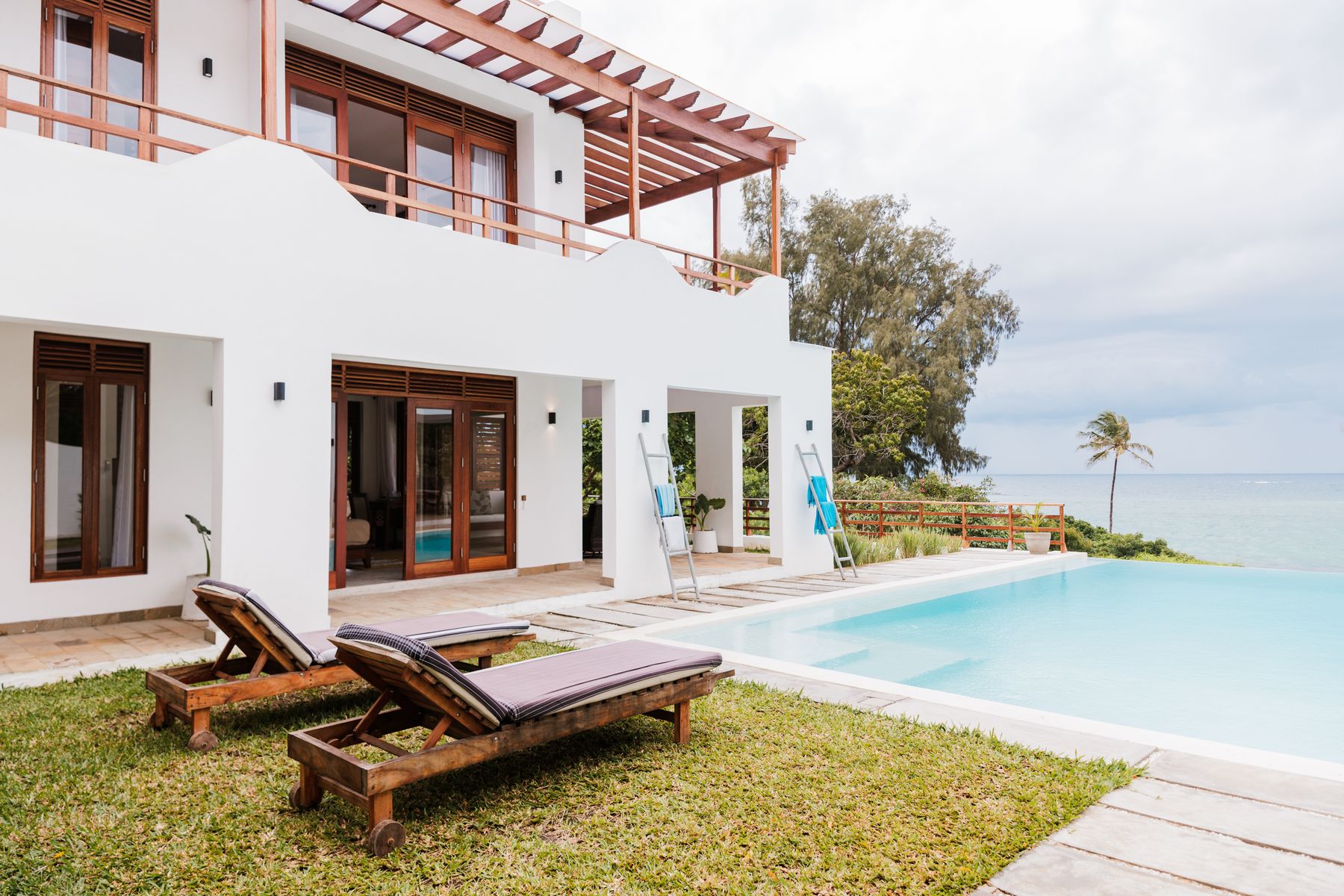 Sun loungers beside the pool with the ocean behind